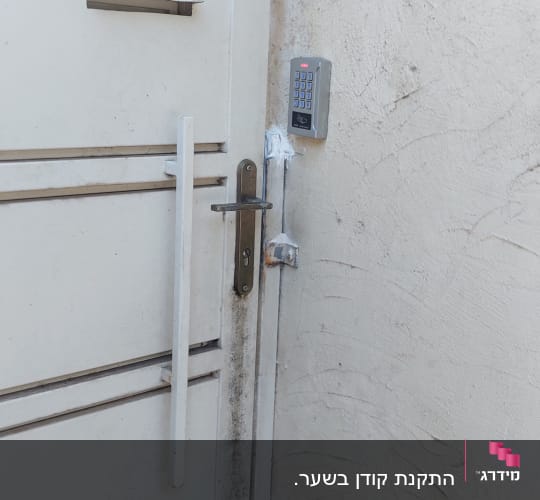 מקודד דלת מותקן על קיר ליד שער לבן